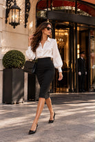 Chemise Alma blanche à col chemisier et manches longues bouffantes, portée avec une jupe noire ajustée